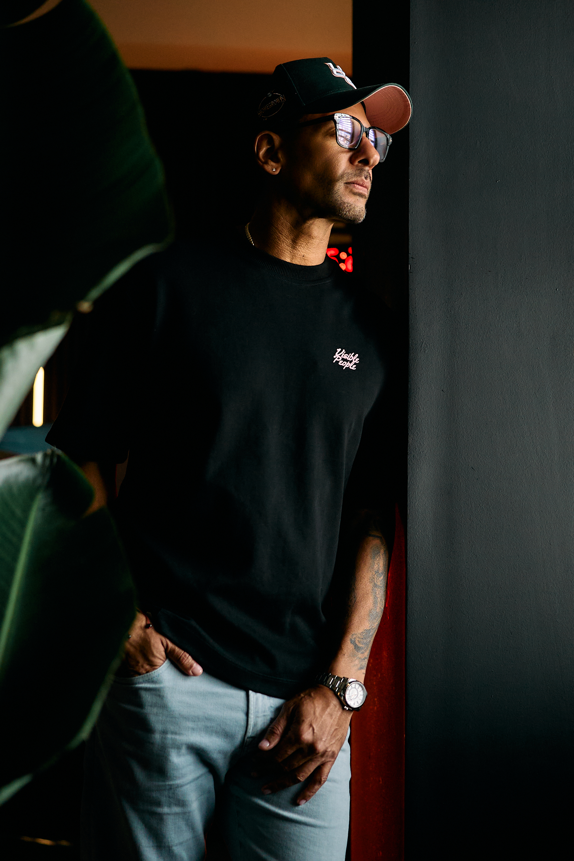 Erik Bankston wearing a black cap and glasses, standing beside a window.